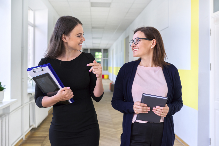 Two female teachers walking down a school corridor